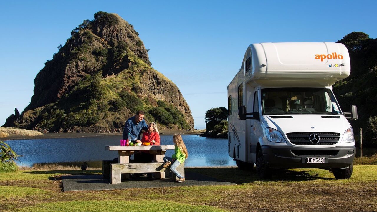 Familie beim Picknick vor Apollo Wohnmobil in Neuseeland