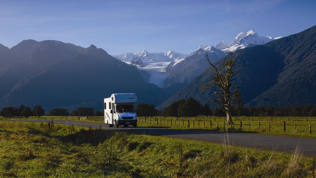 Wohnmobil auf einer Landstraße in Neuseeland mit Bergen