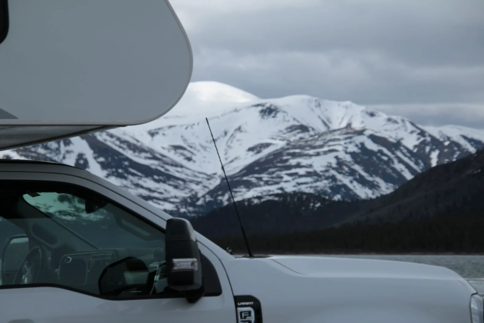 Ein Camper vor einer verschneiten Berglandschaft.