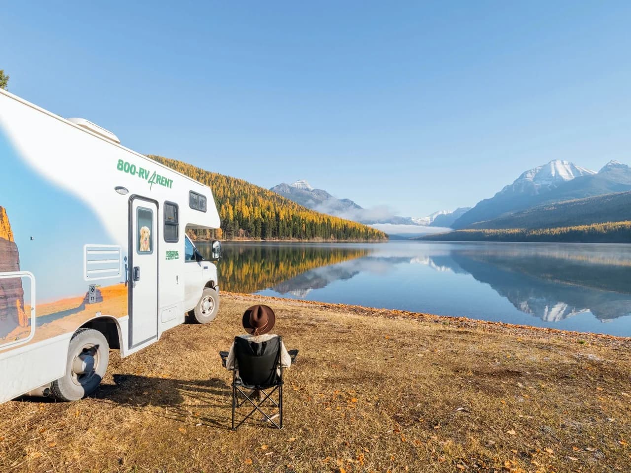 Person sitzt neben ihrem Wohnmobil an einem See in den USA.