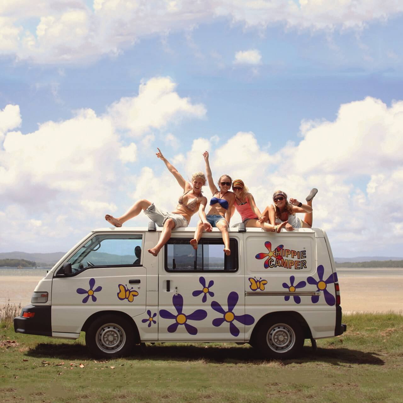 Gruppe junger Leute auf dem Dach eines Hippie Campers in Australien
