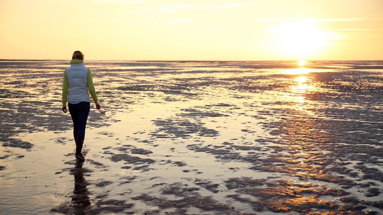 Eine Frau geht über das Wattenmeer
