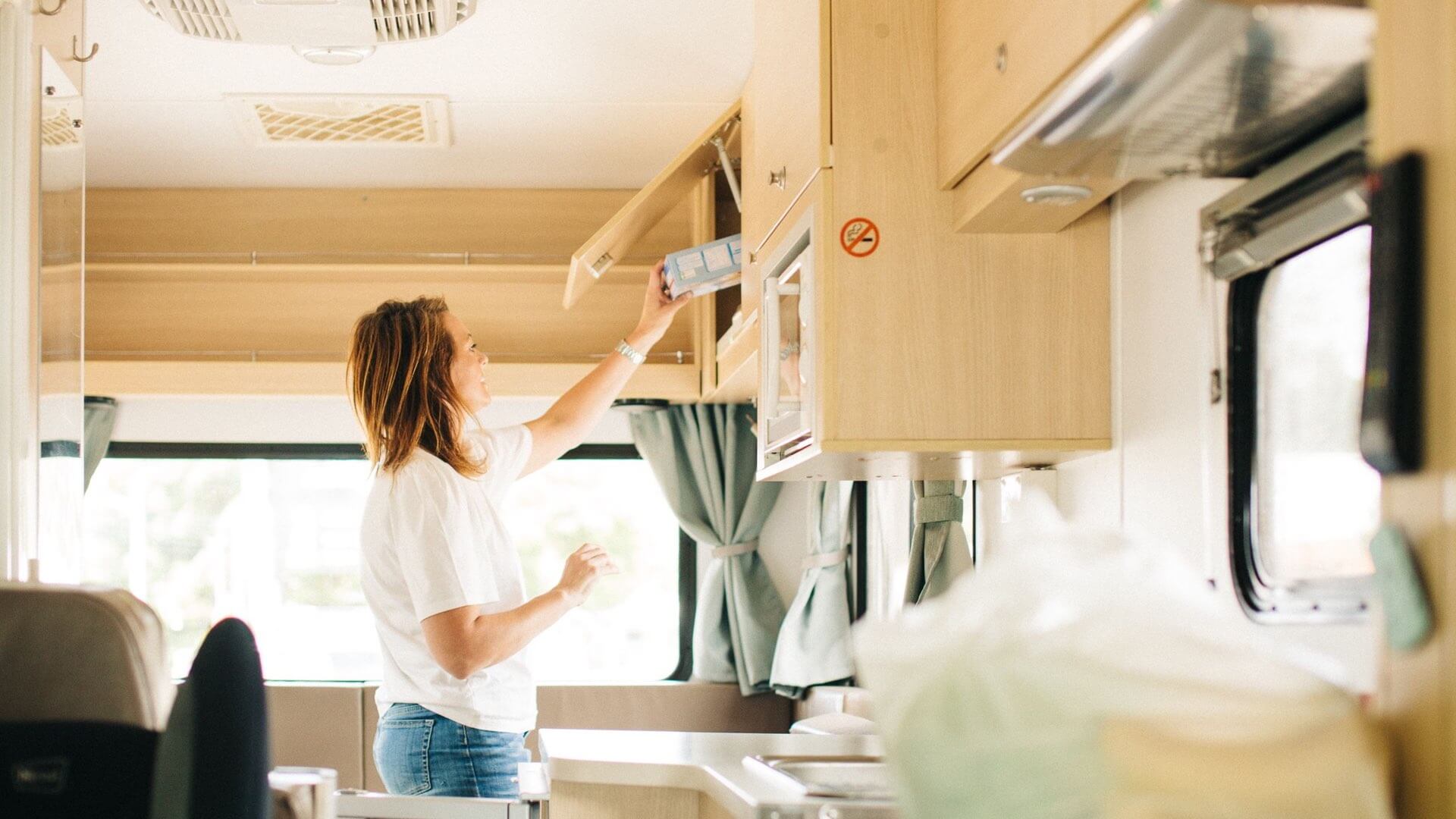 Eine Frau räumt die Küche im Wohnmobil ein