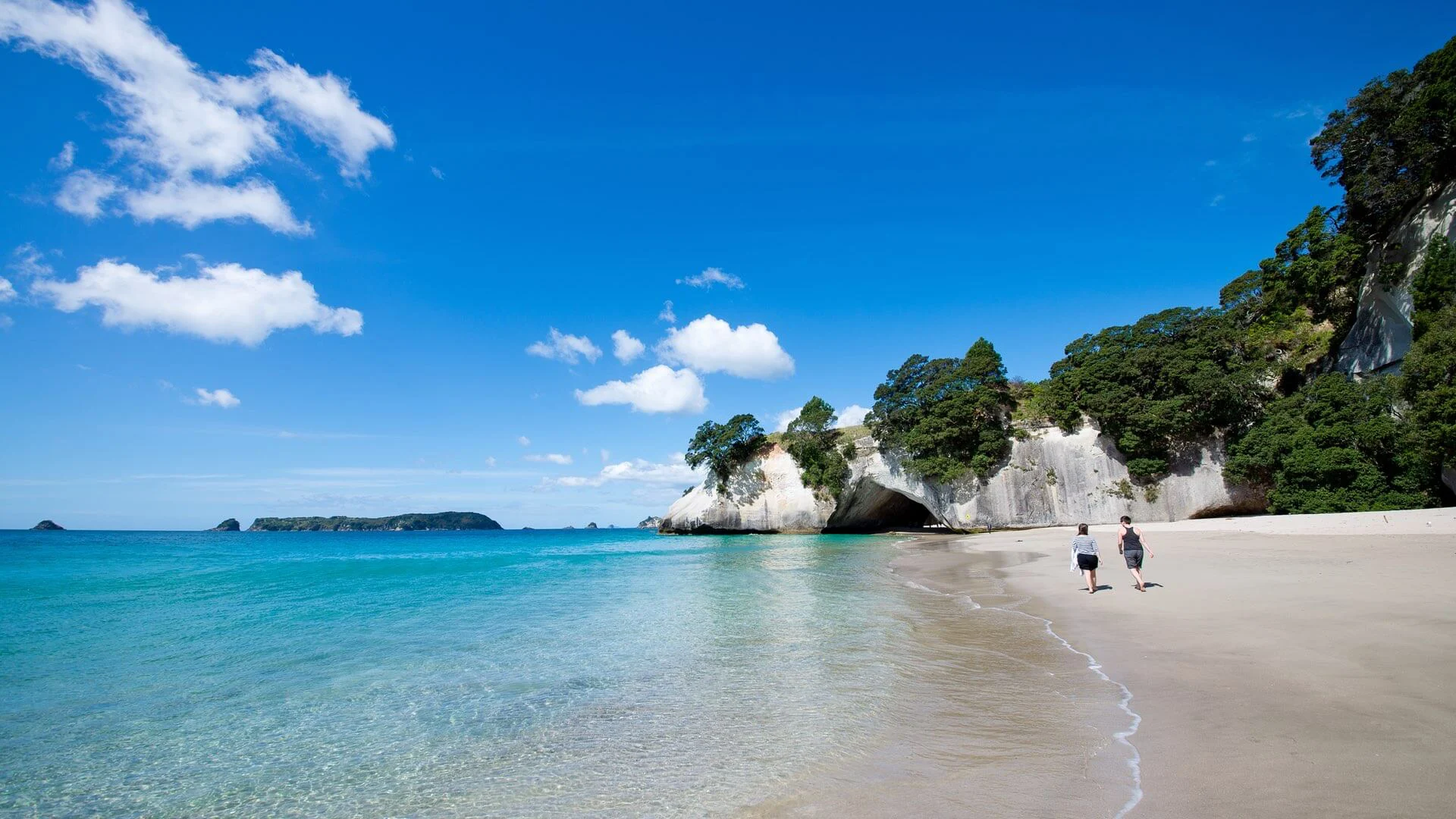 Zwei Personen spazieren am Strand beim Cathedral Cove