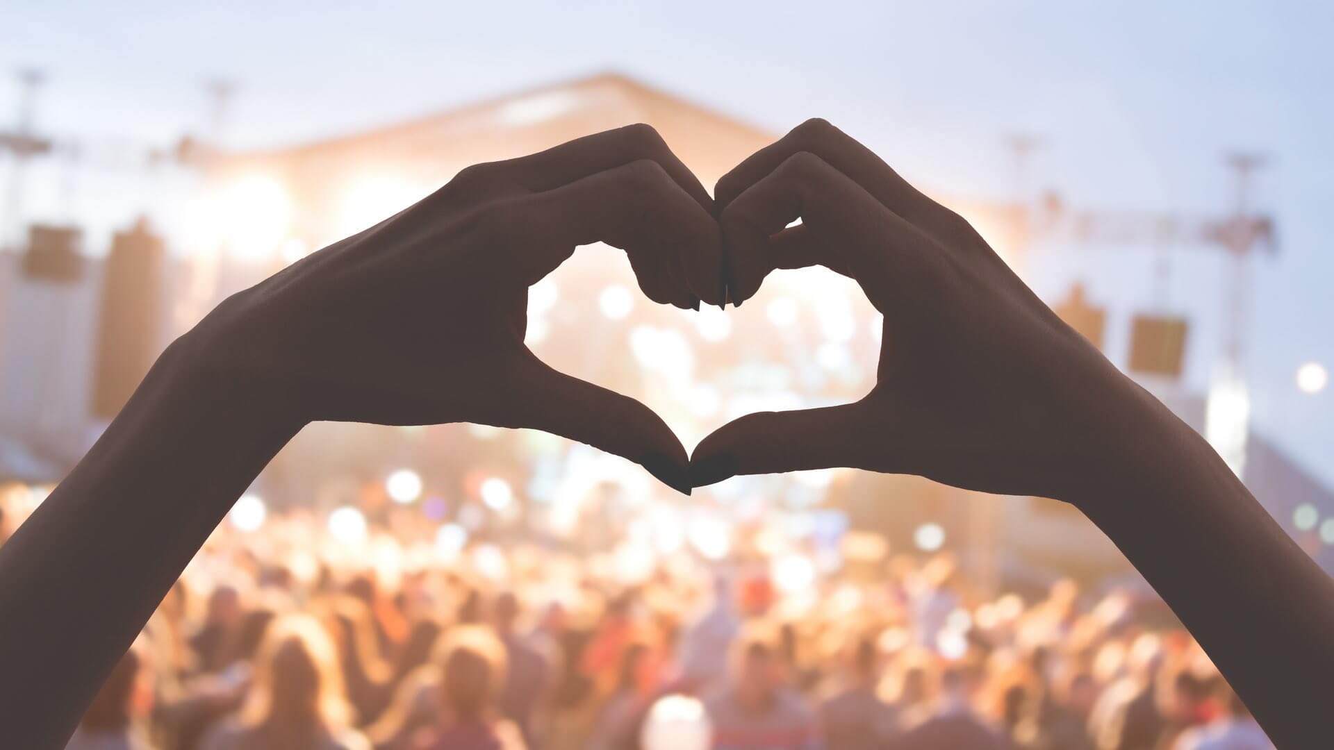 Zwei Hände formen ein Herz auf einem Festival