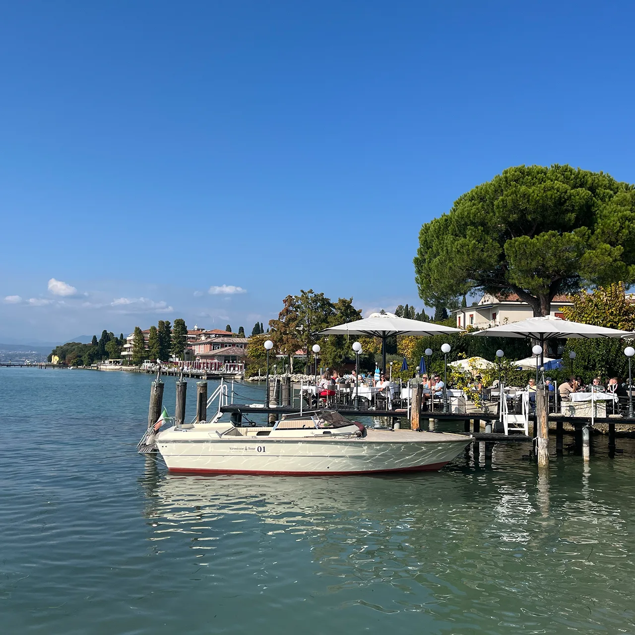 Blick auf den Garda See und seiner schönen Kulisse mit einem Restaurant auf dem Steg in Sirmione in Italien.