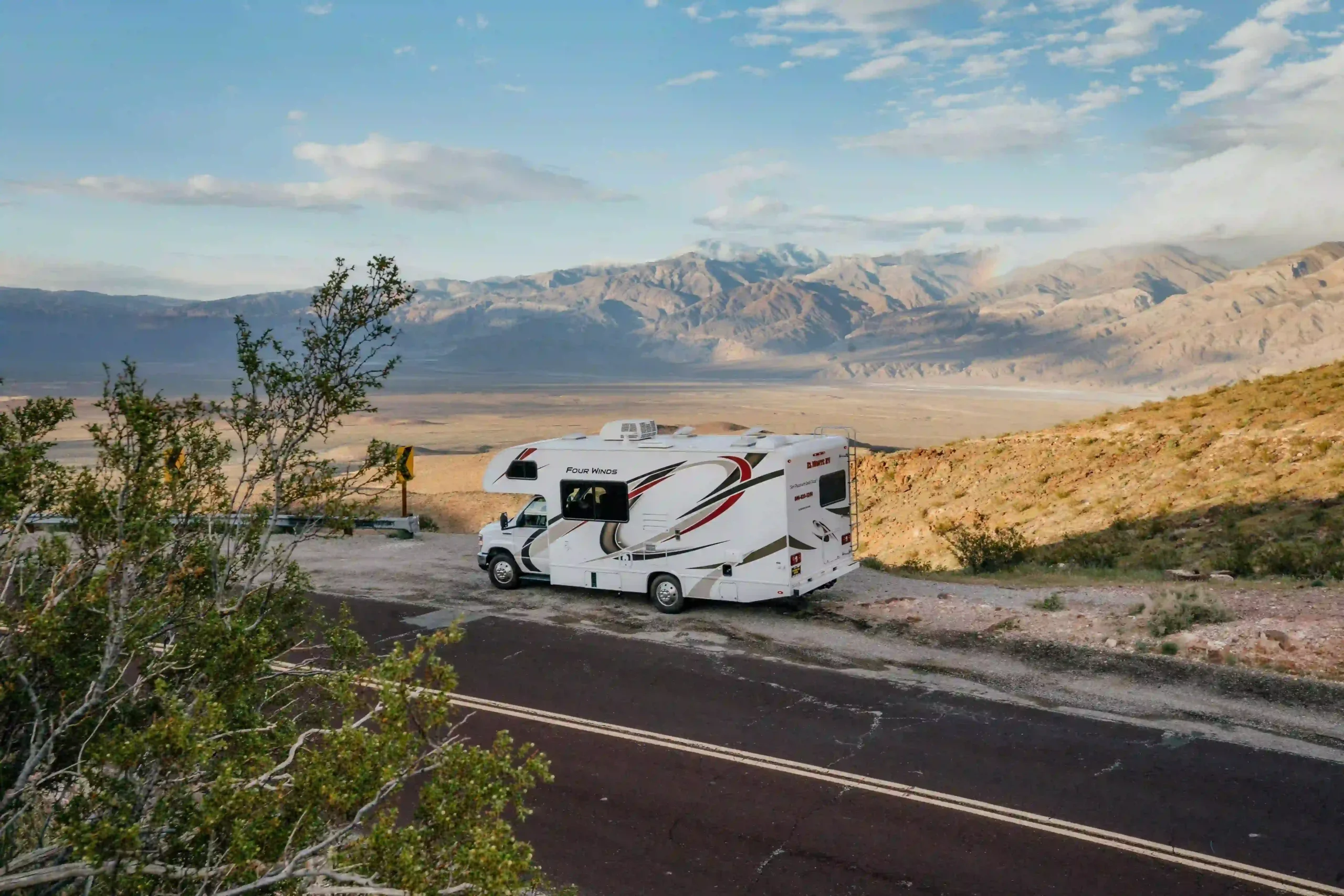 Ein weißes Wohnmobil parkt an einer Bergstraße vor der weiten Wüstenkulisse des Death Valley.