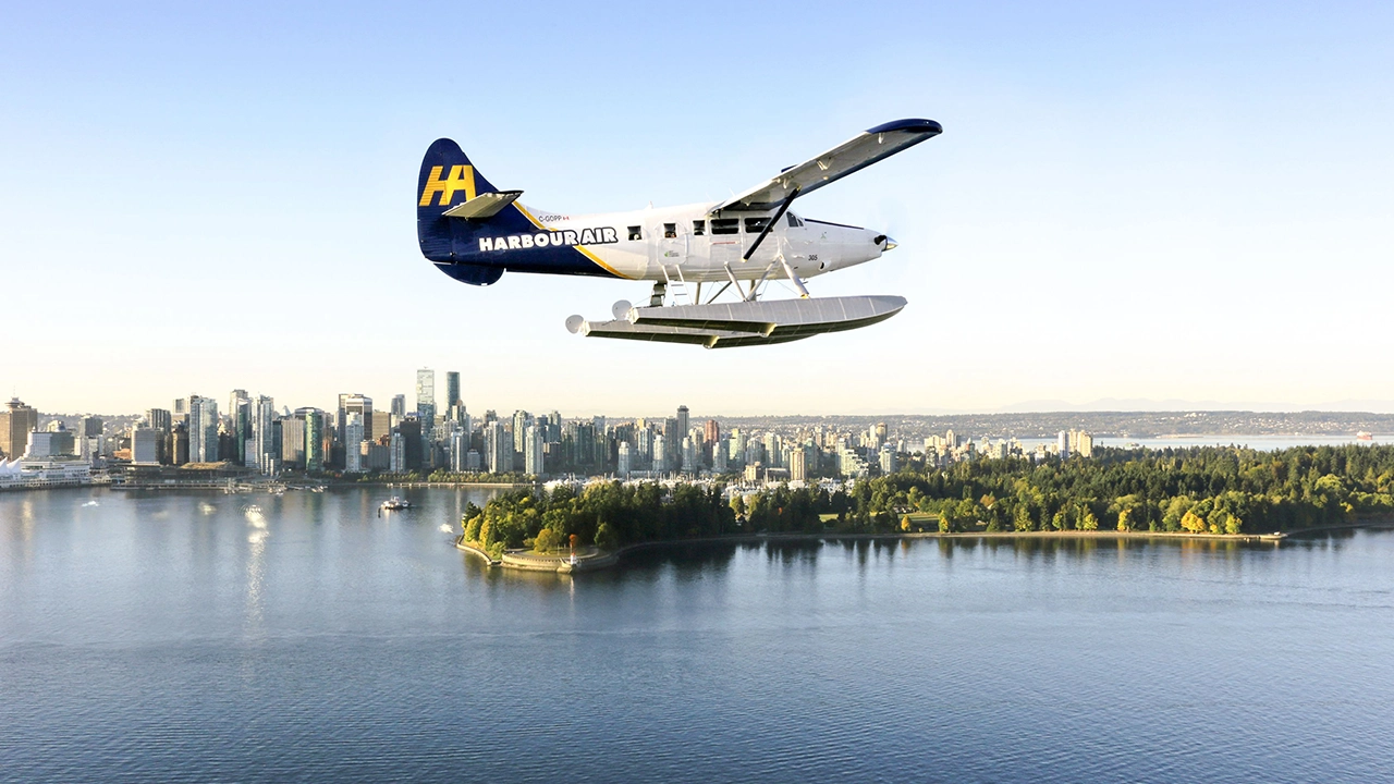 Ein Wasserflugzeug der Harbour Air vor der Skyline der Stadt Vancouver in Kanada.