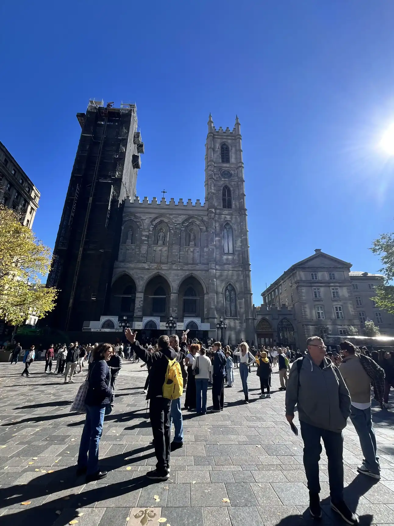 Besucher stehen auf dem sonnigen Platz vor der Kirche Notre-Dame.
