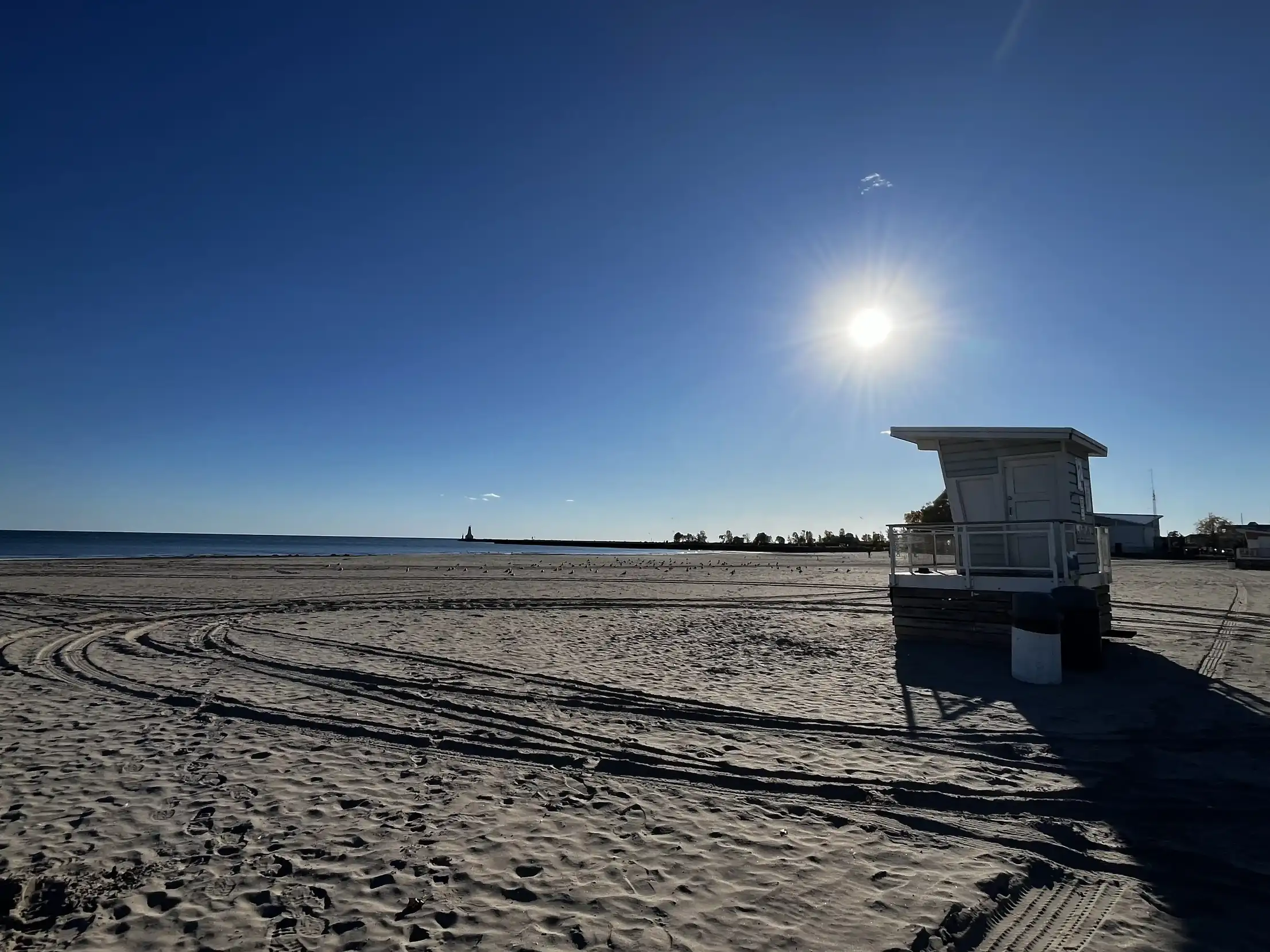 Rettungsschwimmerhütte und Reifenspuren im Sand.