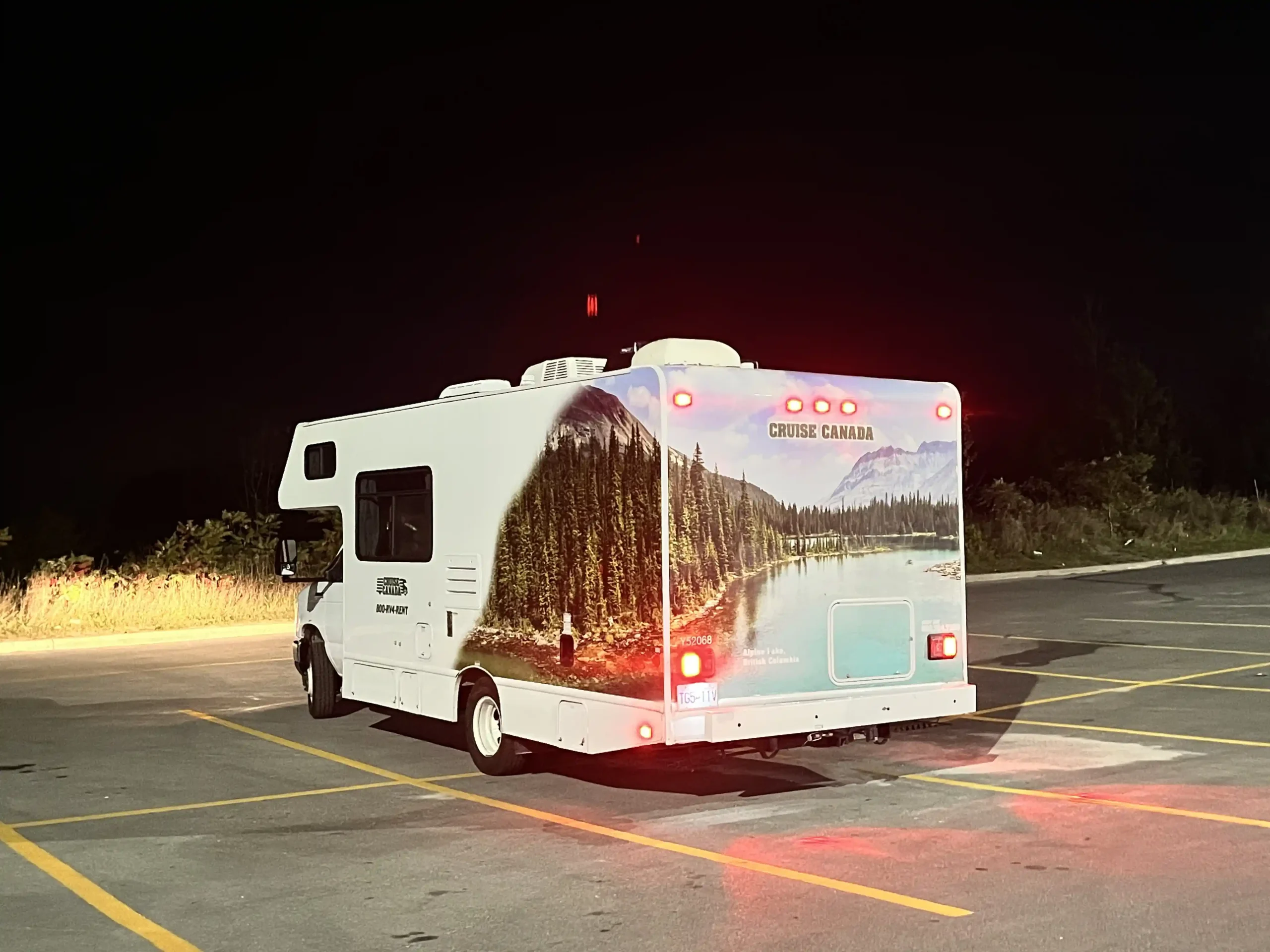 Wohnmobil steht nachts auf leerem Parkplatz.