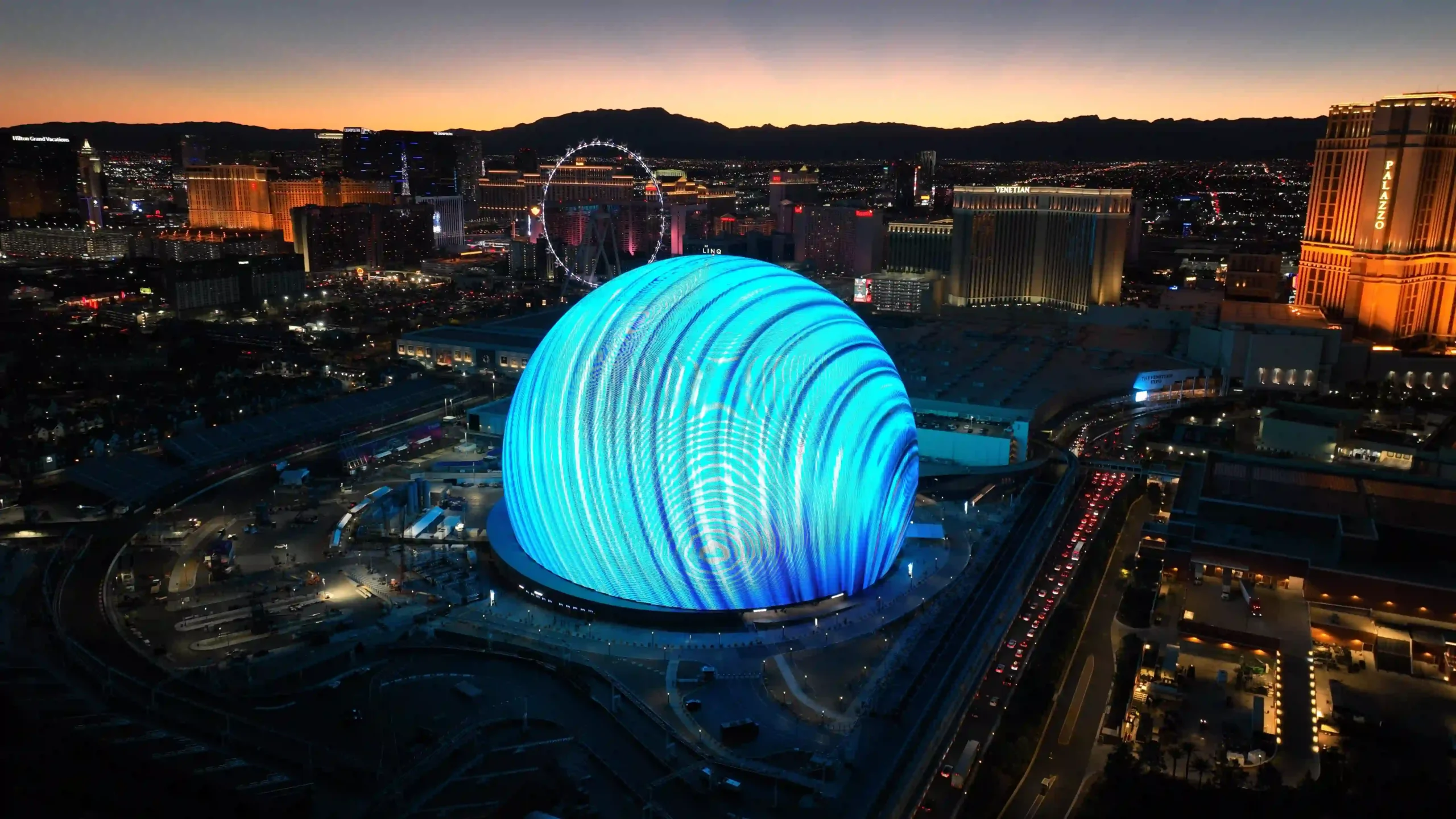 Luftaufnahme von Las Vegas bei Nacht mit der dominanten, blau leuchtenden Sphere im Vordergrund.