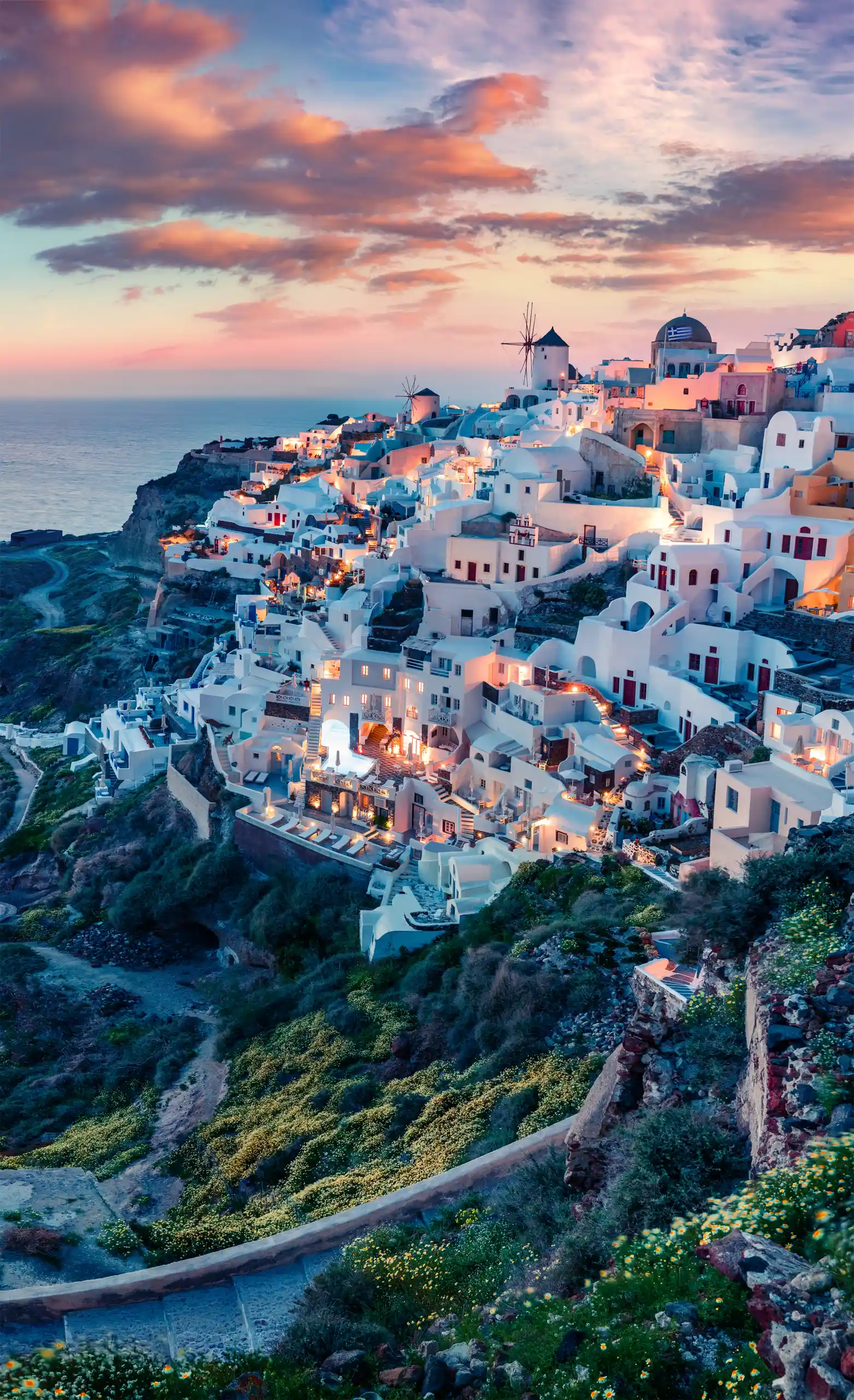 Blick auf Oia auf Santorini in Griechenland bei Sonnenaufgang mit Wolken am Himmel.