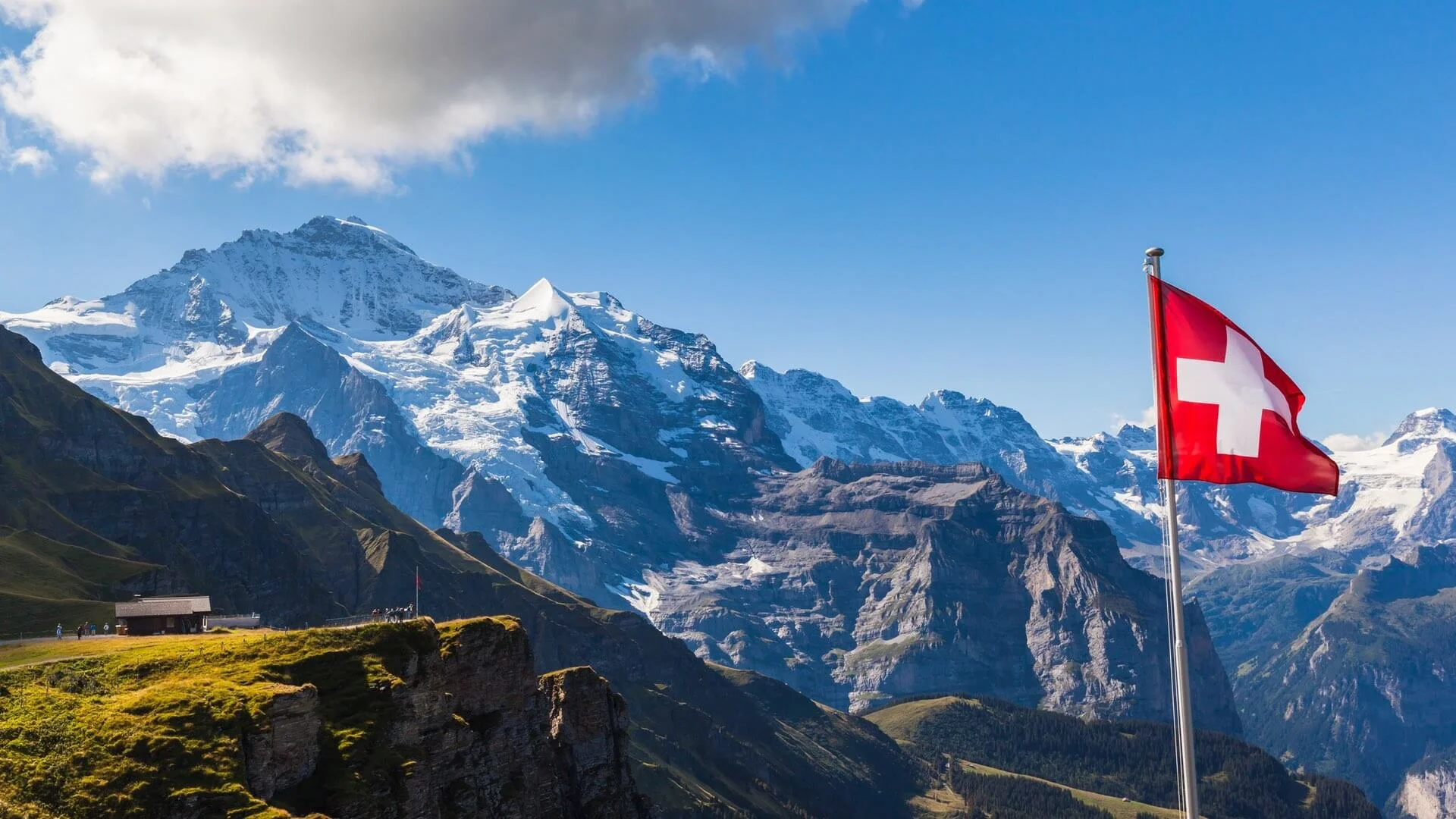 A mountain landscape with a flag of Switzerland in the foreground
