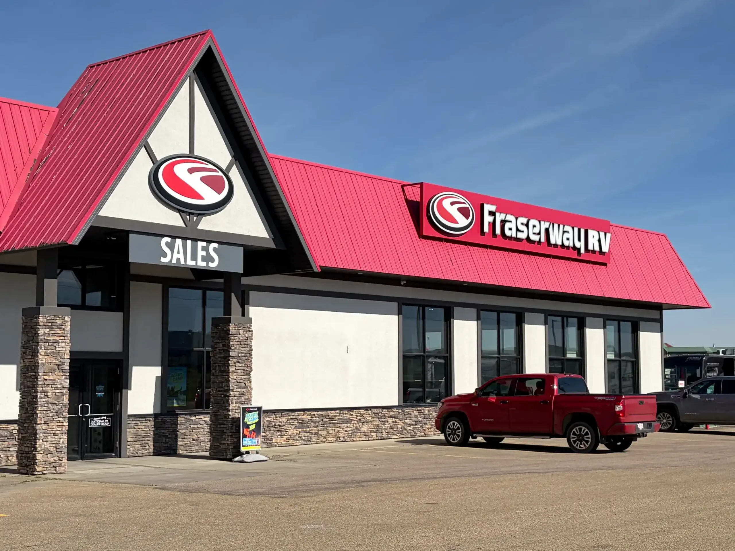 The storefront of the Fraserway RV rental and sales depot in Edmonton. White building with a red roof.