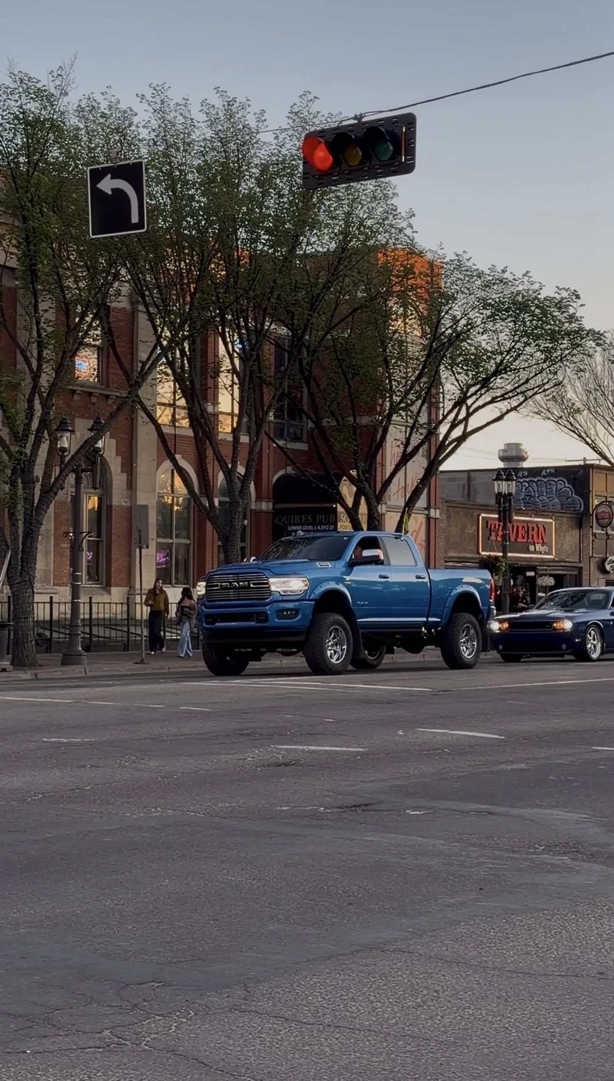 A bright blue, lifted pickup truck on a city intersection.