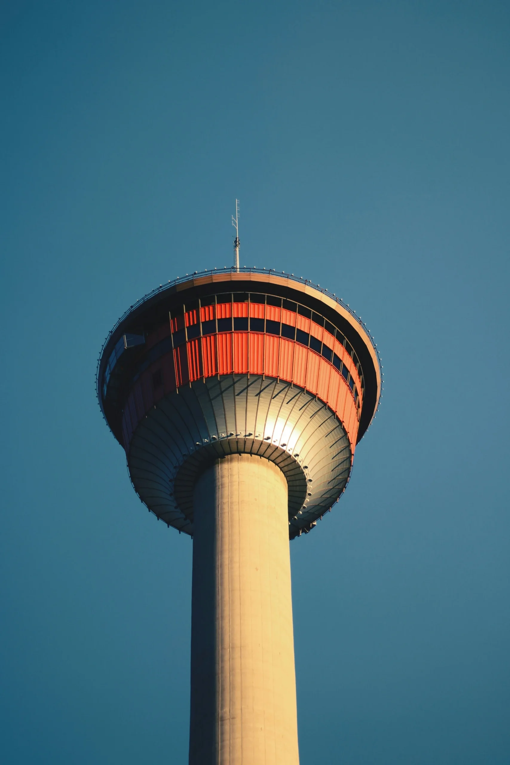 A low-angle shot looking up at the Calgary Tower against a clear, deep blue sky.