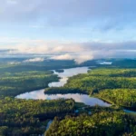 An aerial view of a winding river, interconnected lakes, and dense forest in Algonquin Provincial Park, Ontario.