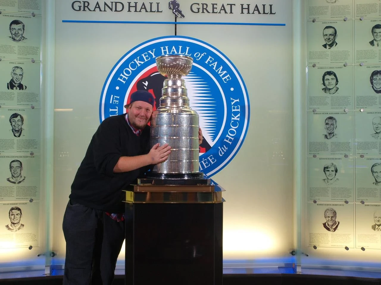 A person smiling while hugging the Stanley Cup at the Hockey Hall of Fame.