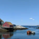 Weathered wooden fishing standing over calm water with two small boats anchored in the foreground.