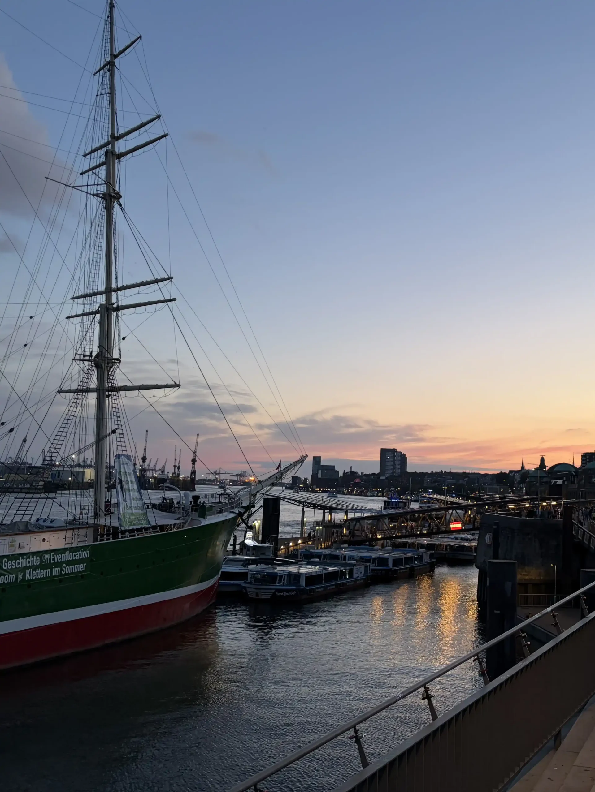 Boats docked along the harbour during a warm sunset over the Elbe River.