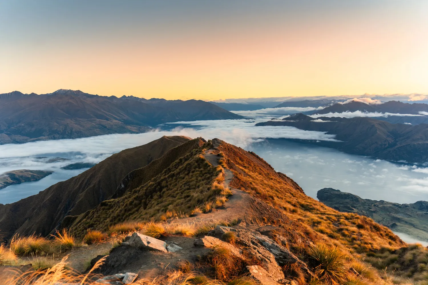 Dramatic mountain ranges of the Southern Alps rising out of the clouds at Roys Peak, New Zealand.