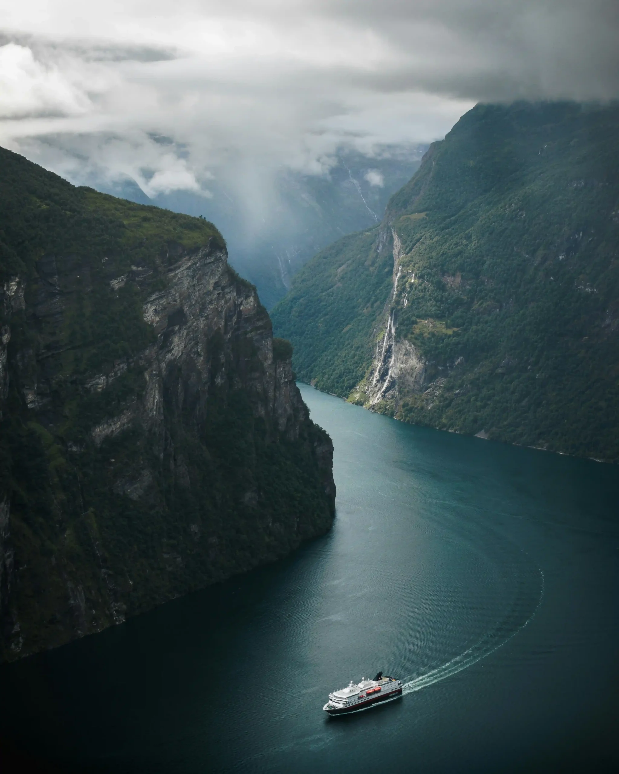A cruise ship navigates the dramatic curves of Geirangerfjord.