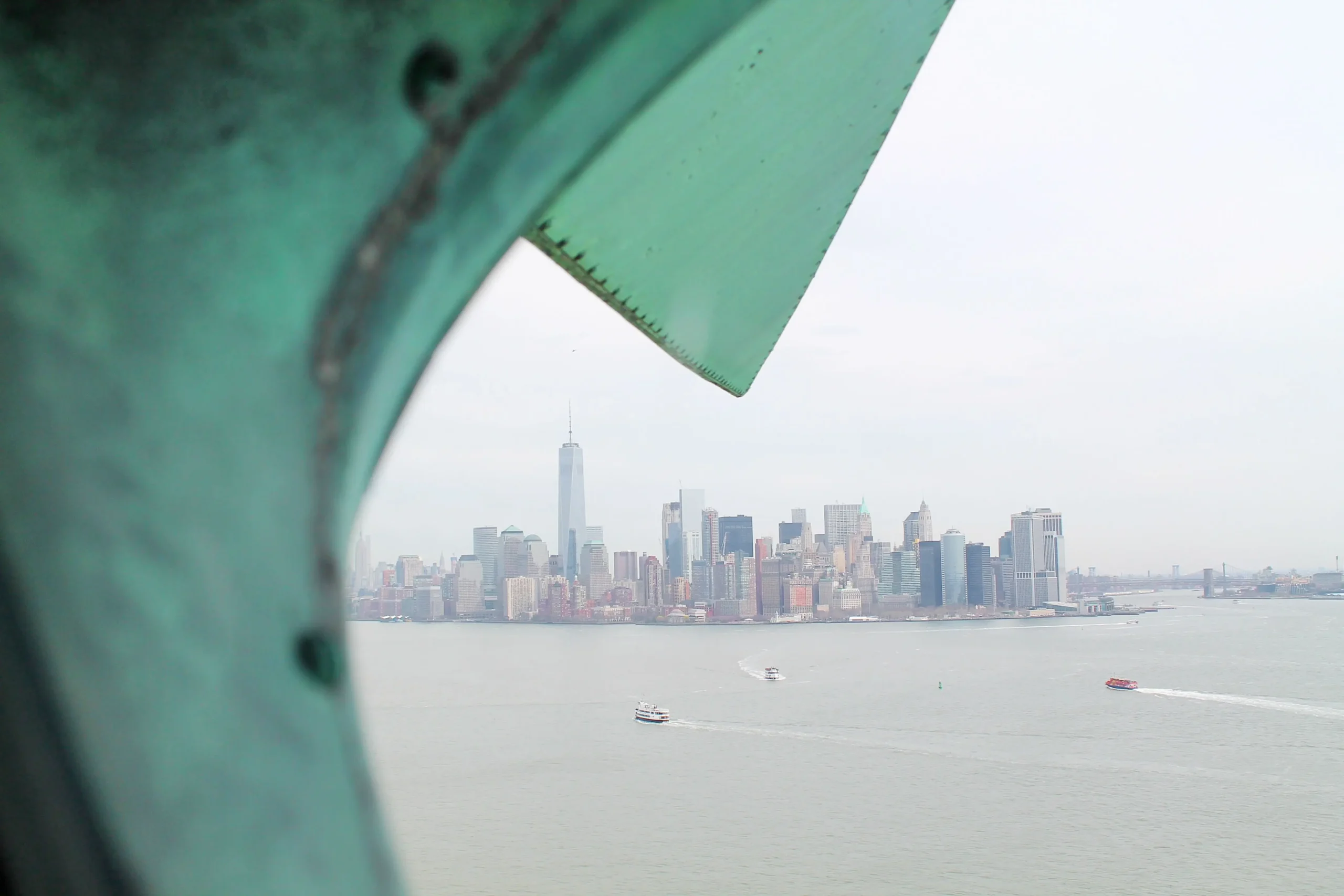 View of the New York City skyline framed by a part of the Statue of Liberty.
