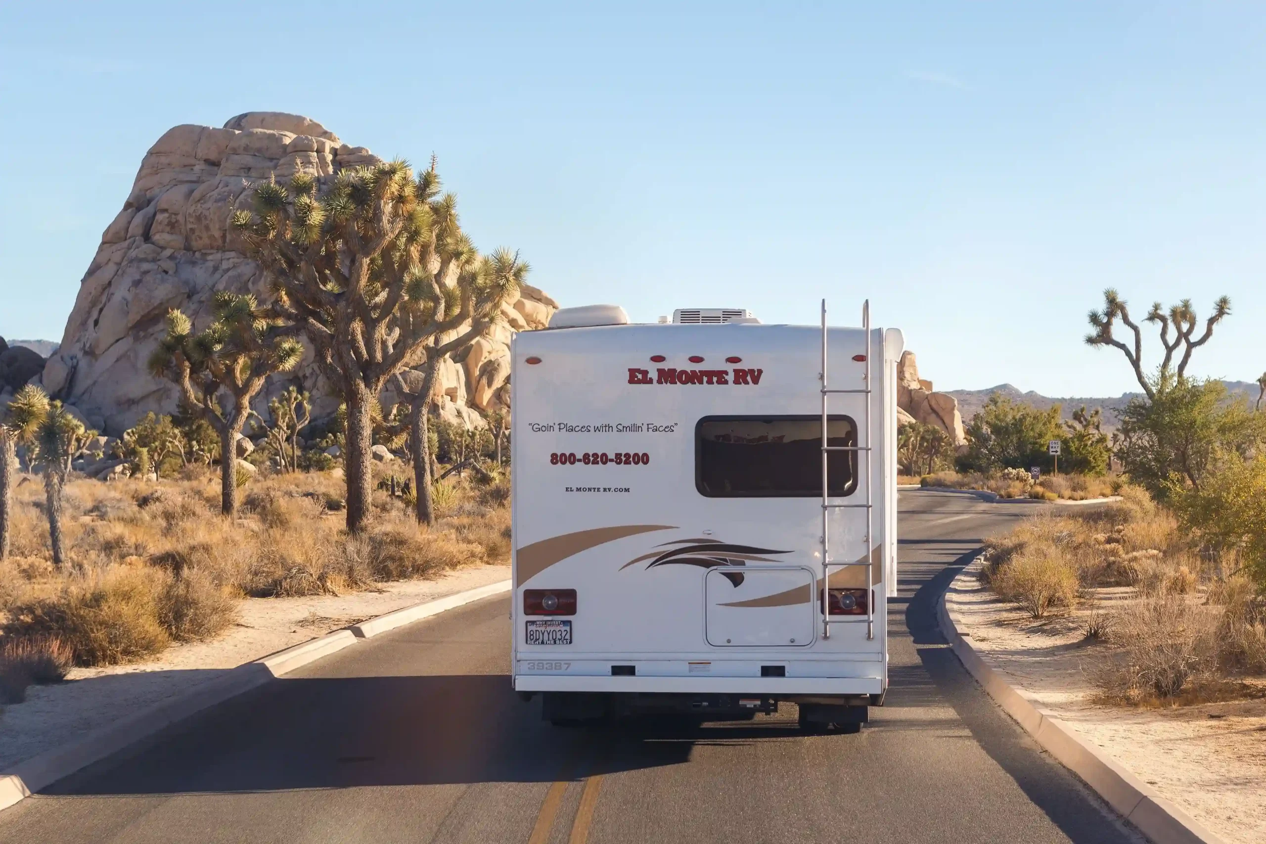 An El Monte RV is captured from behind, traveling down a road in Joshua Tree National Park.