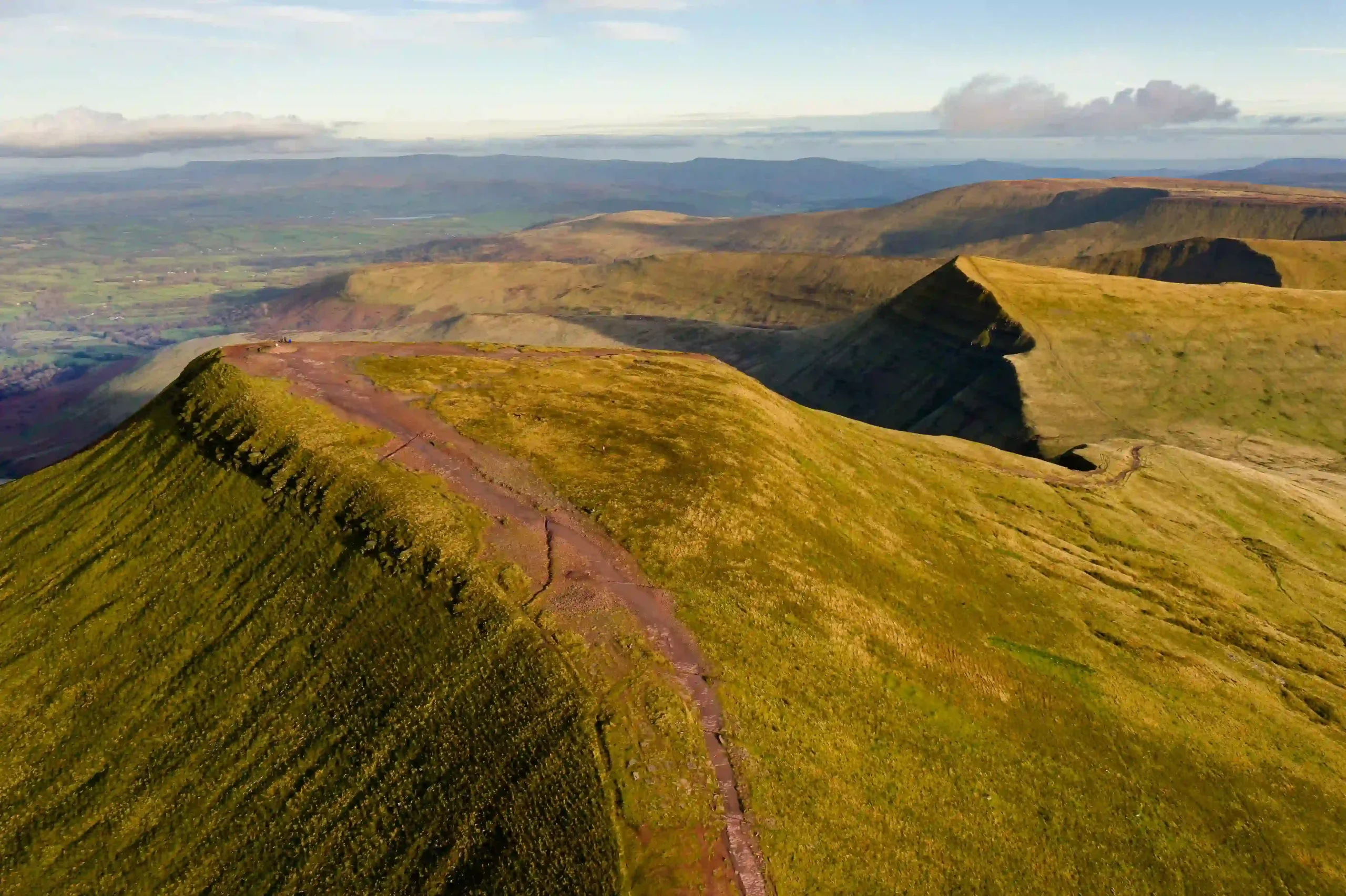 Sunlit green peaks and deep valleys create a beautiful landscape across the Brecon Beacons in Wales.