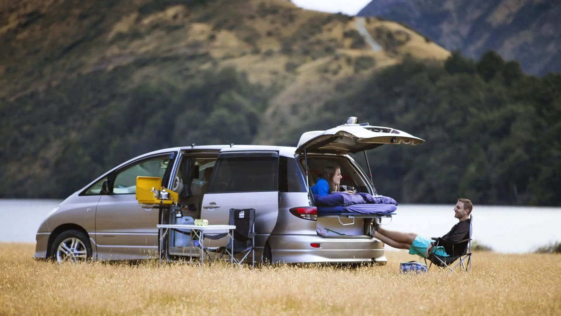 Un couple fait du camping avec un van aménagé Spaceships en Australie au bord d\'un lac.