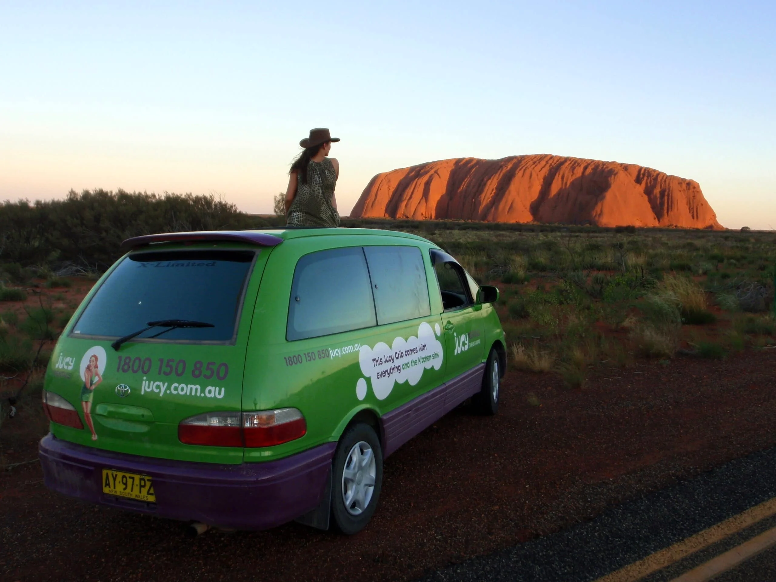 Van Jucy en Australie garé au bord de la route devant l'Ayers Rock ou Uluru en Australie